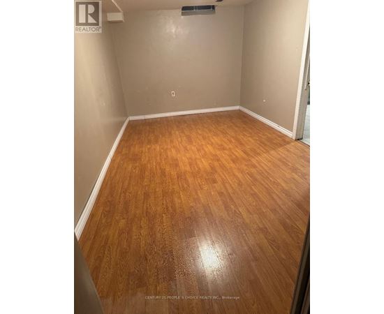 A room with wooden flooring and a realtor logo on the wall.