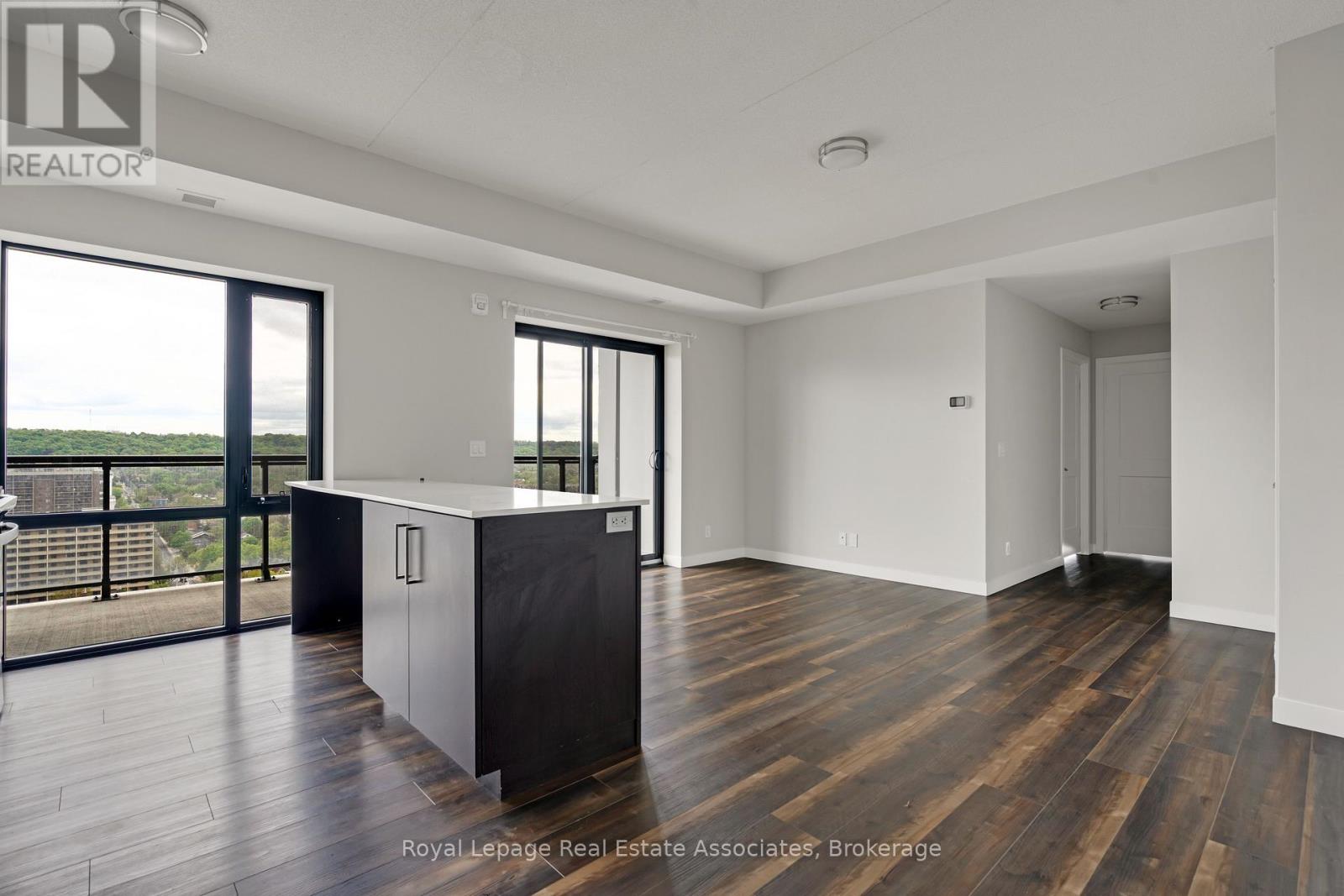 A spacious room with wooden floors and a large window overlooking the water.