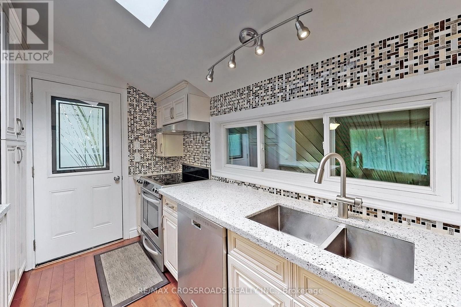 A kitchen with a white tile backsplash and a skylight.