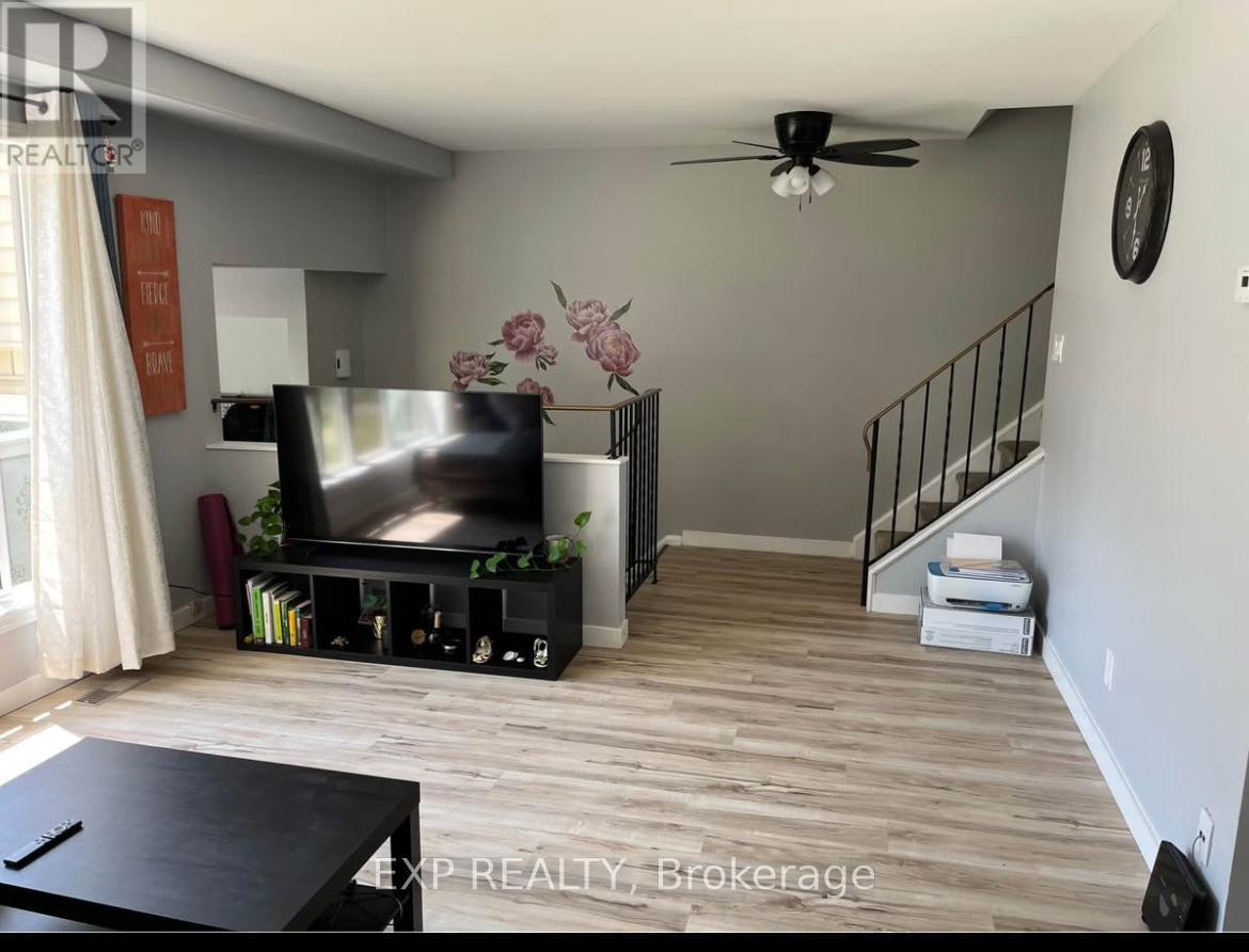A living room with a television, a staircase, and a ceiling fan.