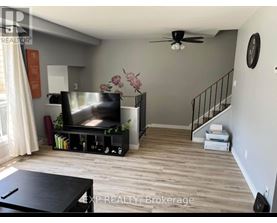 A living room with a television, a staircase, and a ceiling fan.