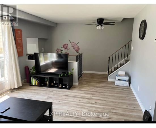 A living room with a television, a staircase, and a ceiling fan.