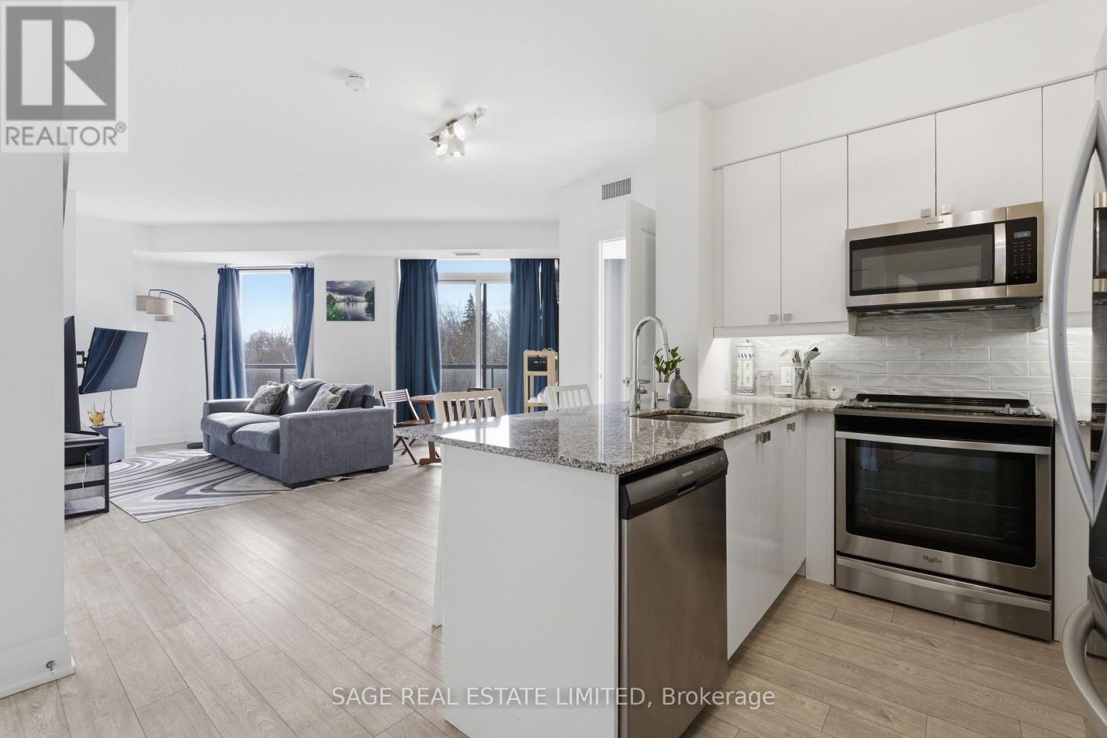 A modern kitchen with stainless steel appliances and a dining area with a couch and chairs.