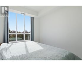 A bedroom with a large bed and a window overlooking a tree-filled landscape.