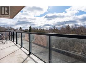 A balcony with a glass railing and a view of trees and sky.
