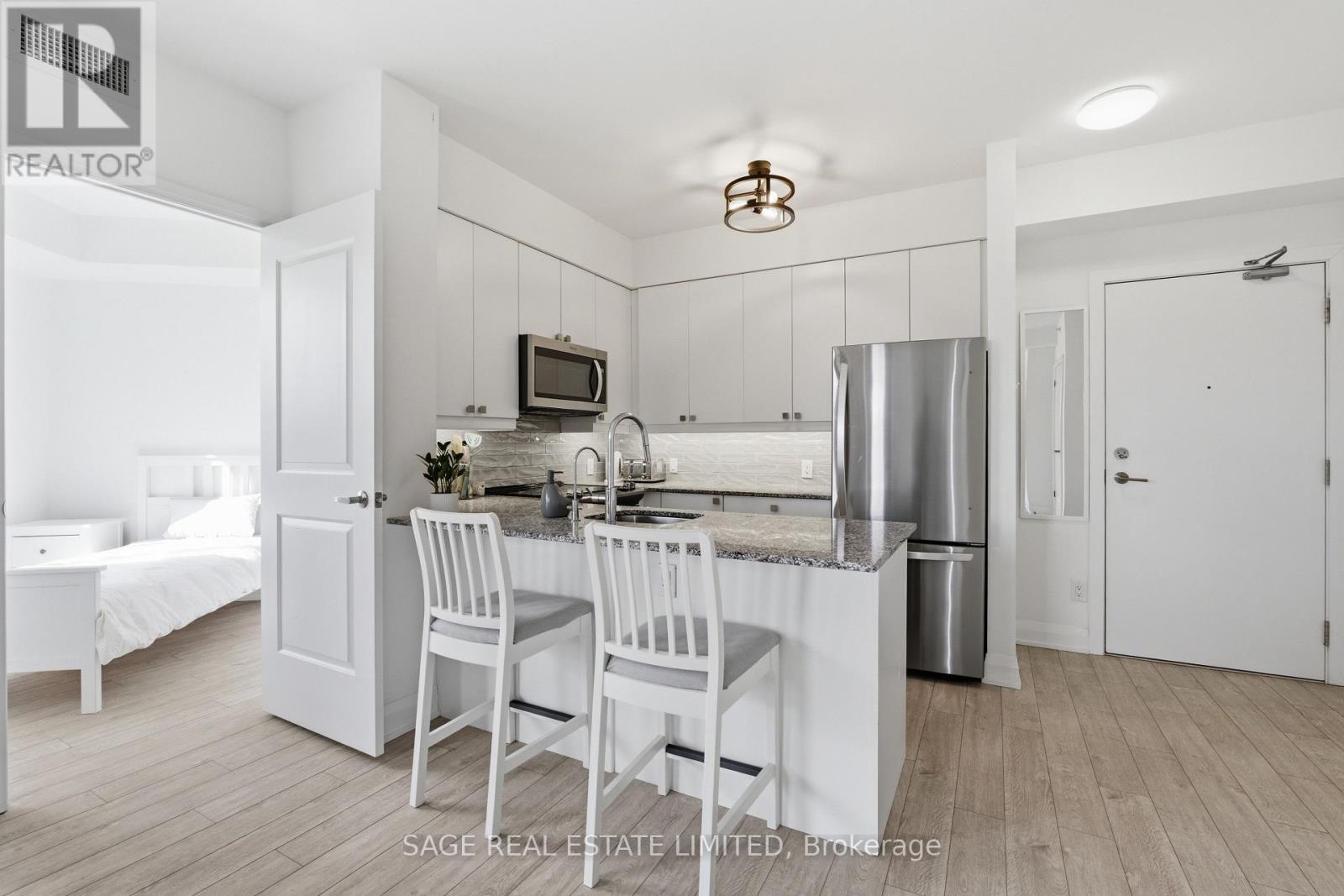 A kitchen with white cabinets and a stainless steel refrigerator.