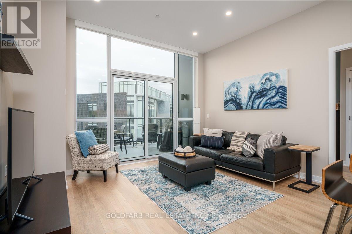 A living room with a black couch, a chair, and a painting on the wall.