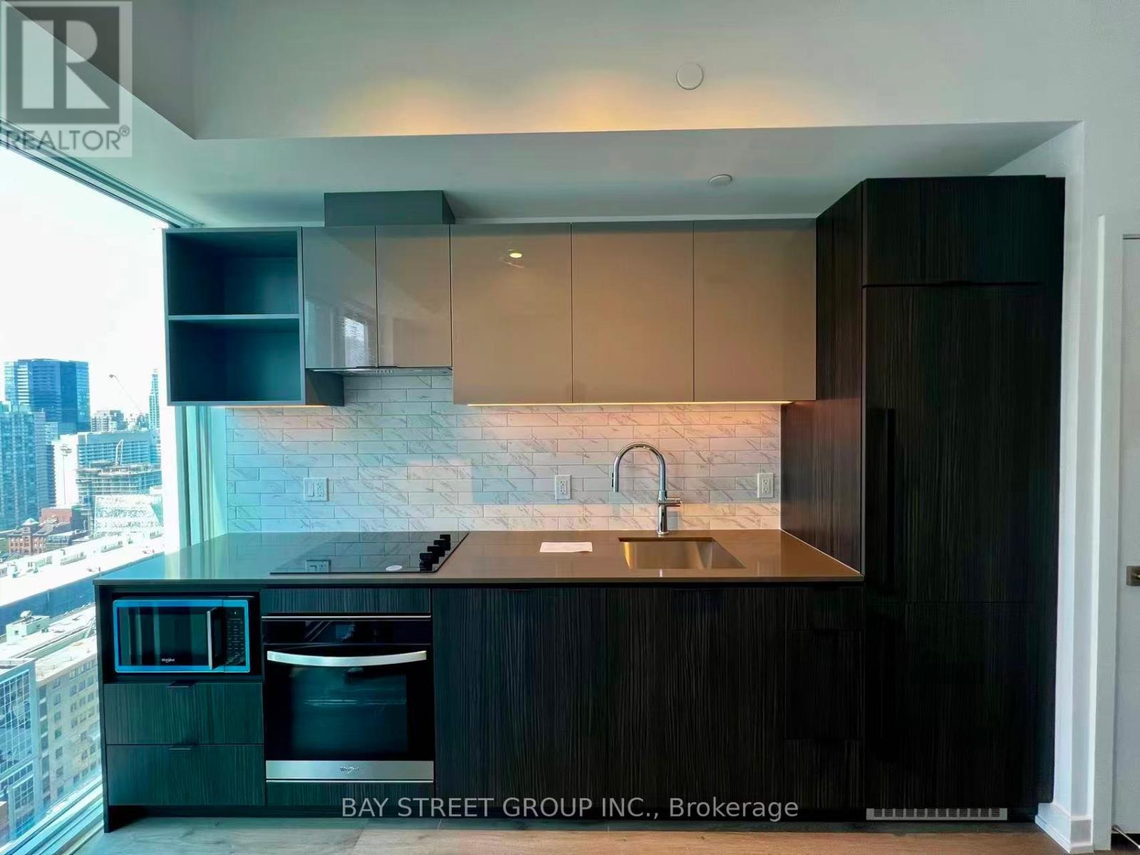 A modern kitchen with dark wood cabinets and a marble backsplash.