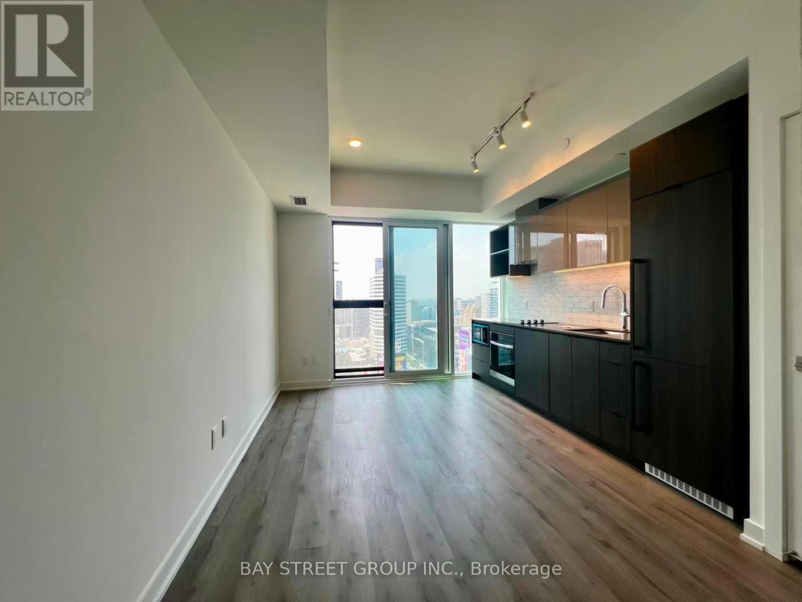A spacious room with wooden floors and a large window overlooking the city.