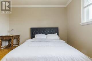 A bedroom with a white bed and a wooden table.