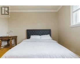 A bedroom with a white bed and a wooden table.
