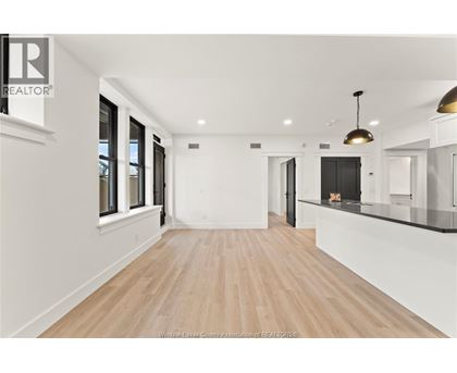 A spacious room with wooden flooring and white walls.