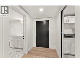 A black door is in the middle of a white room.