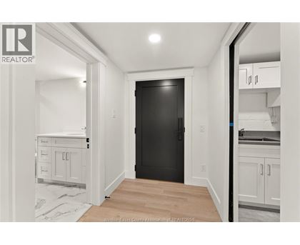 A black door is in the middle of a white room.