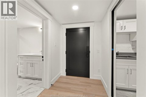 A black door is in the middle of a white room.