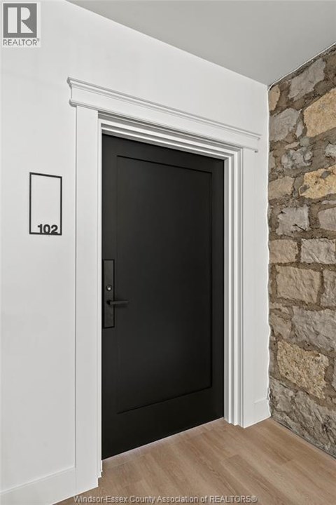 A black door with a white frame and a number 102 on the wall above it.