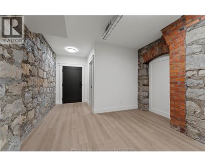 A hallway with a stone wall on the left and a brick wall on the right.