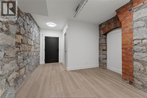 A hallway with a stone wall on the left and a brick wall on the right.