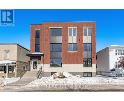 A modern brick building with a glass entrance and a staircase leading to the door.