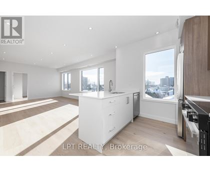 A modern kitchen with white cabinets and a large window.