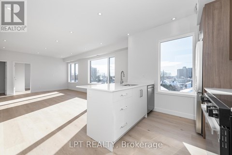 A modern kitchen with white cabinets and a large window.