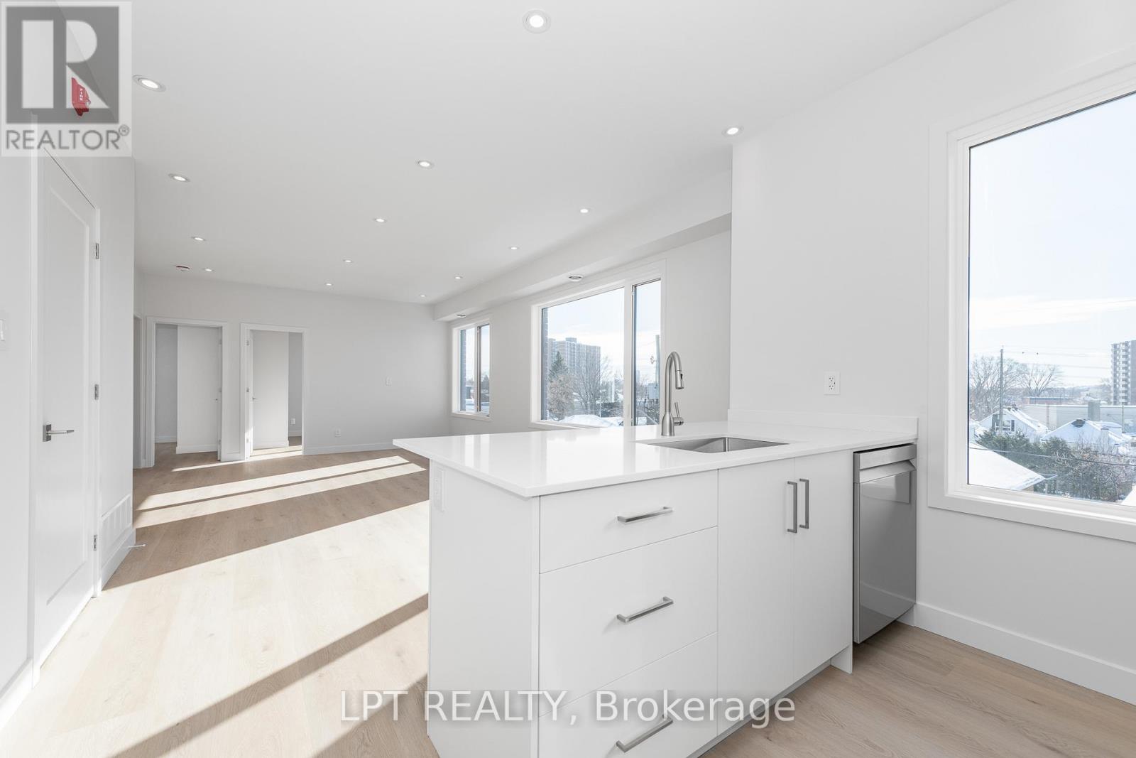A modern kitchen with white cabinets and a large window overlooking a cityscape.