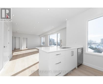A modern kitchen with white cabinets and a large window overlooking a cityscape.