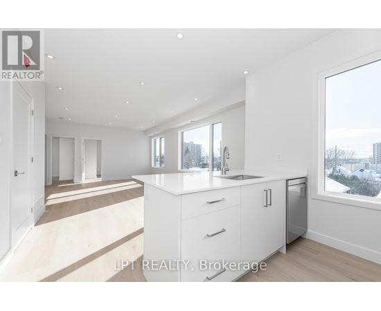 A modern kitchen with white cabinets and a large window overlooking a cityscape.