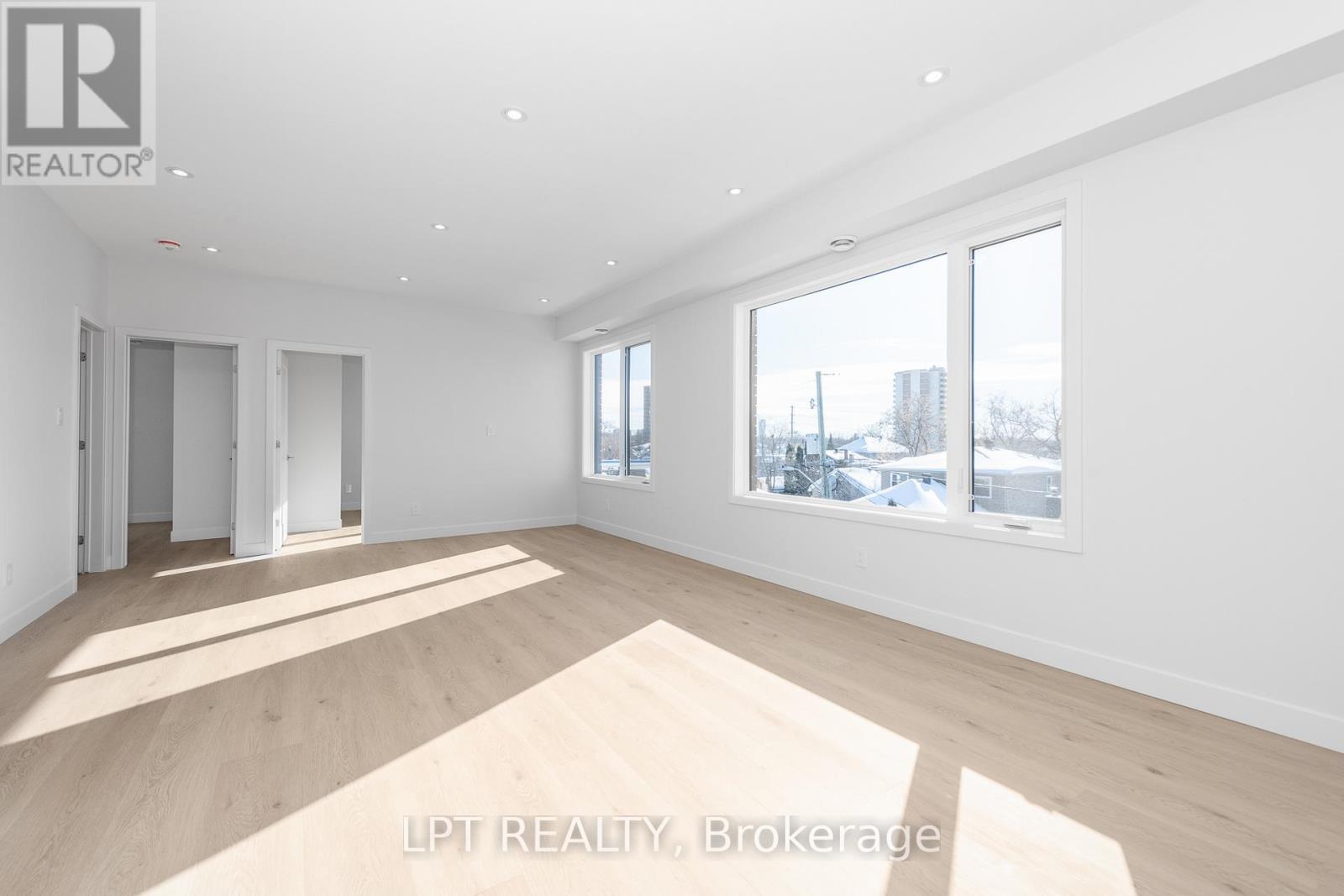 A spacious room with wooden flooring and white walls.