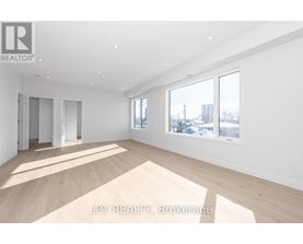 A spacious room with wooden flooring and white walls.