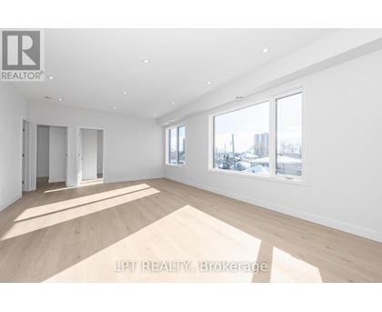 A spacious room with wooden flooring and white walls.