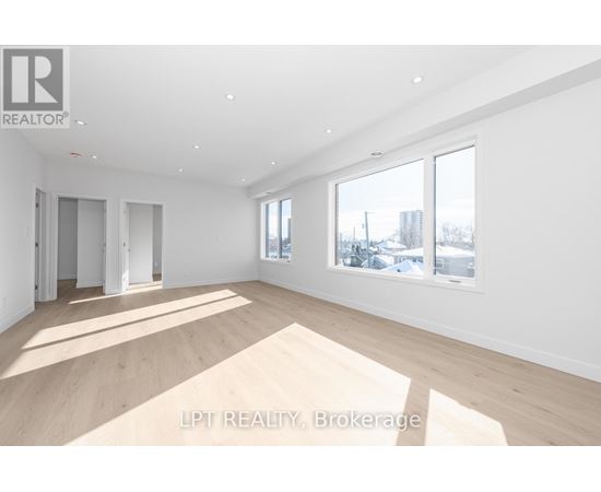 A spacious room with wooden flooring and white walls.