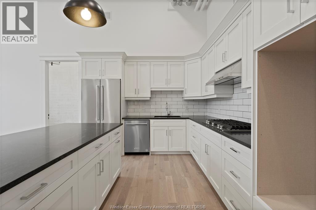 A kitchen with white cabinets and a black countertop.