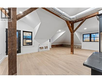 A spacious room with wooden floors and a large wooden beam on the ceiling.