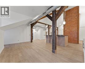 A spacious room with wooden floors and a large wooden beam structure.