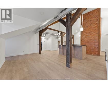 A spacious room with wooden floors and a large wooden beam structure.
