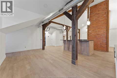 A spacious room with wooden floors and a large wooden beam structure.