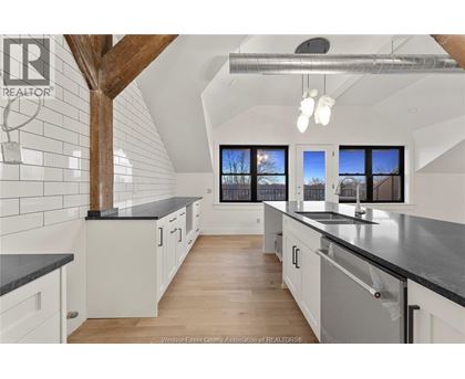 A kitchen with white cabinets and black countertops.
