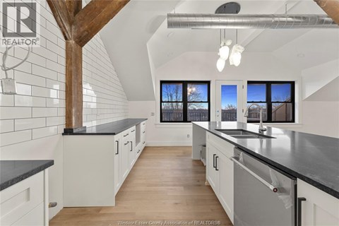 A kitchen with white cabinets and black countertops.