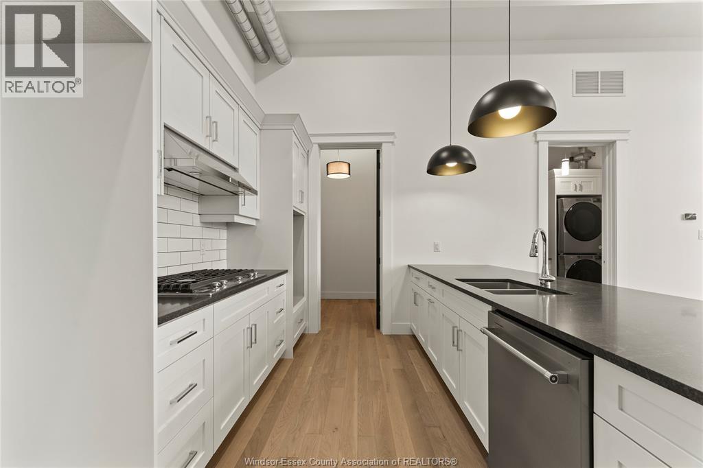 A modern kitchen with white cabinets and a wooden floor.