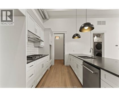 A modern kitchen with white cabinets and a wooden floor.
