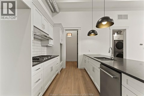 A modern kitchen with white cabinets and a wooden floor.