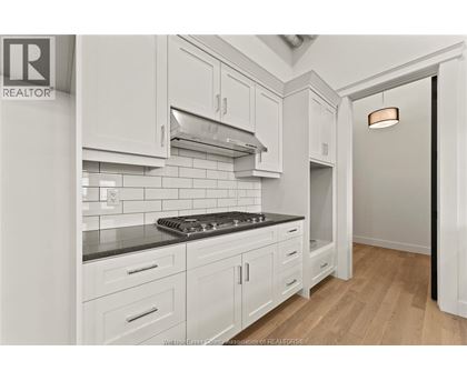 A kitchen with white cabinets and a black stove top.