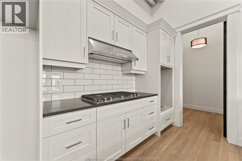 A kitchen with white cabinets and a black stove top.