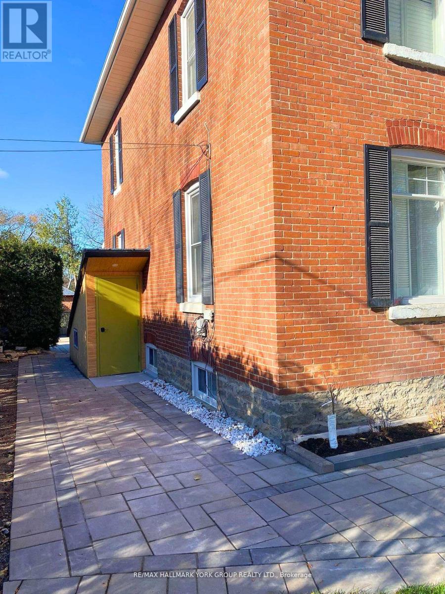 A red brick building with a yellow door and a stone wall.