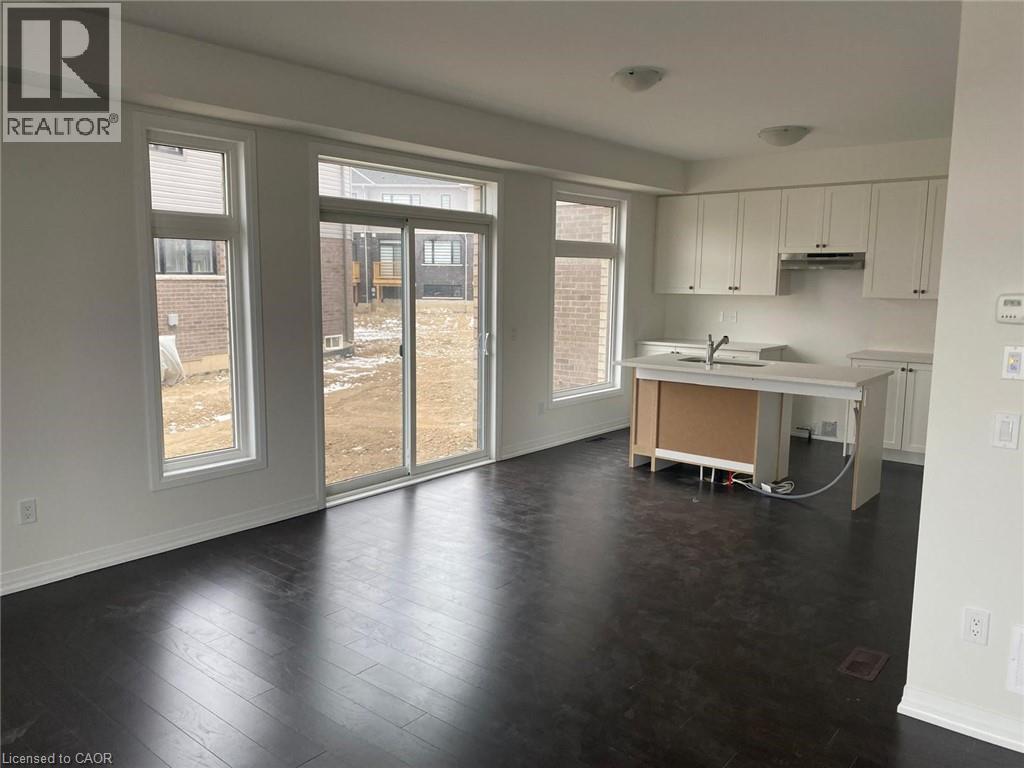 A large empty room with a kitchen area in the middle.