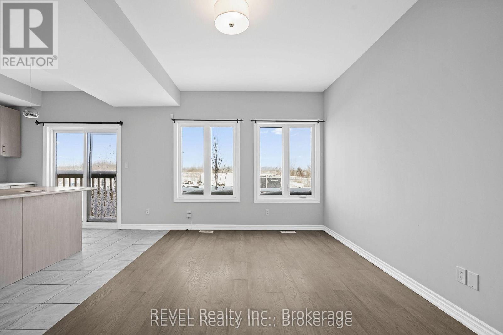 A spacious room with a large window and a wooden floor.