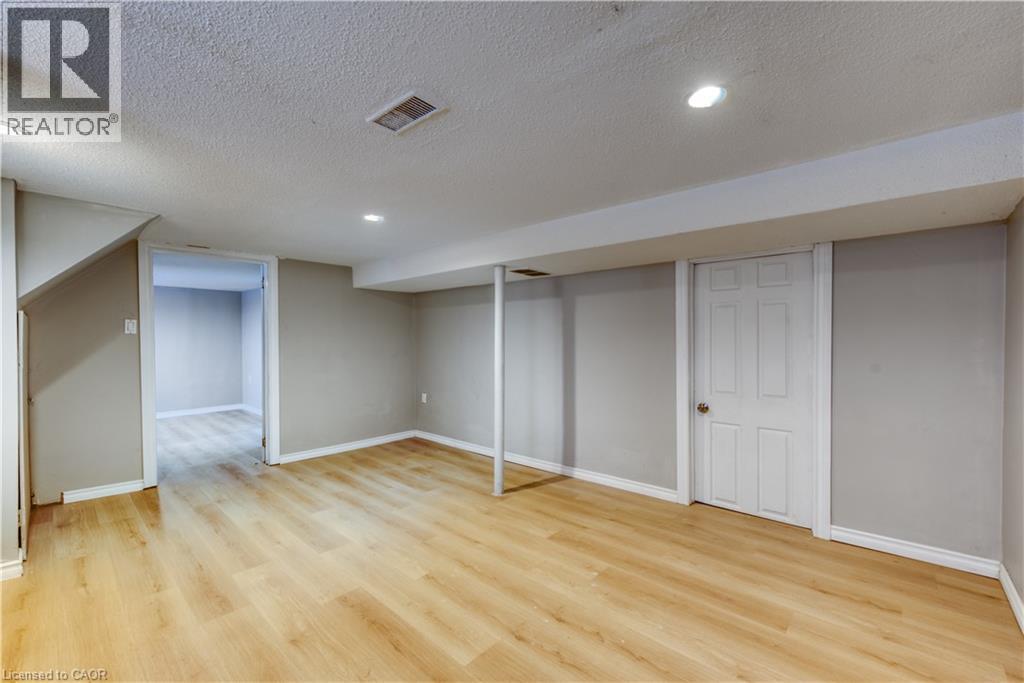 A room with wooden flooring and white walls, with a door on the right side.