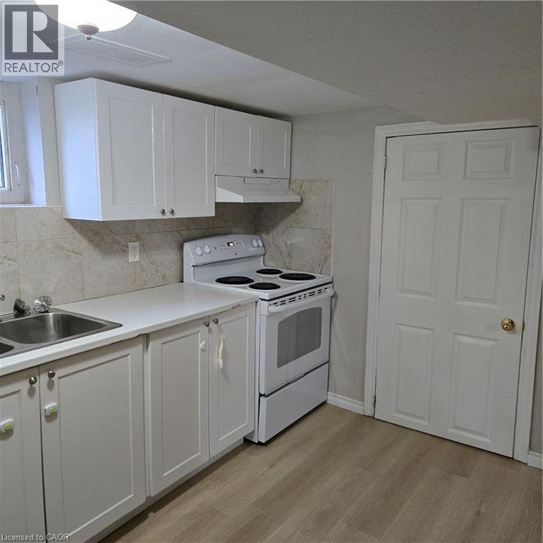 A kitchen with white cabinets and a white stove top oven.