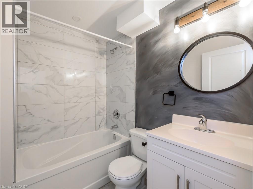 A bathroom with a marble tile shower, white toilet, and sink.